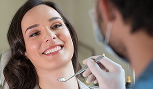 Woman smiling at dentist holding tools