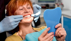 Dentist and smiling woman examine smile in mirror