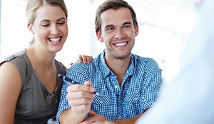 Woman and smiling man holding a pen