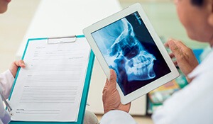 Dentist looks at x-ray on tablet