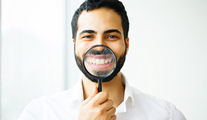 man in white shirt holding magnifying glass to smile