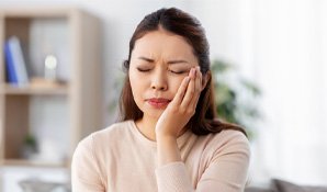 Woman with dark brown hair with tooth pain