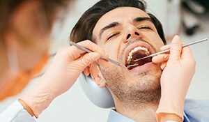 Man receives treatment with two dental tools