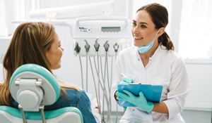 Dentist smiling at patient while taking notes on clipboard