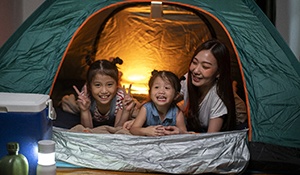 parent with their two children camping out in their living room