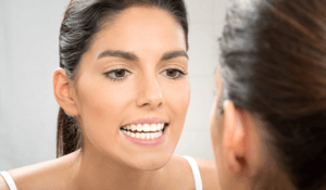 woman looking at teeth in mirror