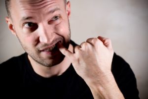 man in black t-shirt picking at his teeth with his pinky finger