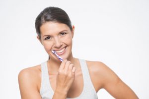 Woman brushing teeth to prevent gum disease with tips from her dentist in Wichita Falls