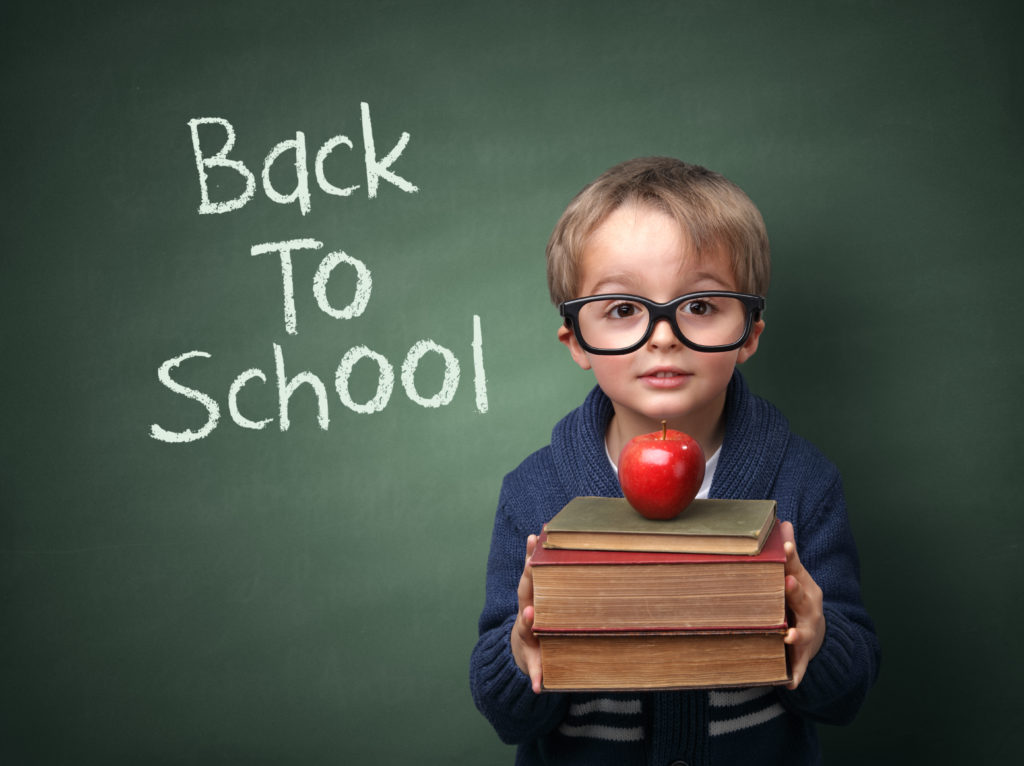 little boy holding books and apple