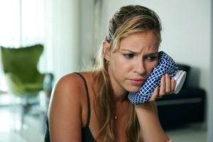 Woman holding compress to her face